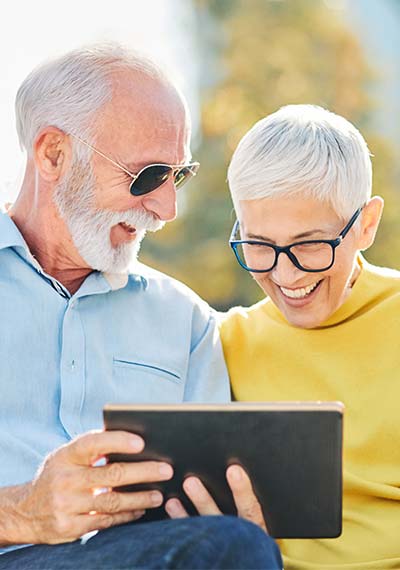 Senior couple smiling while looking at tablet